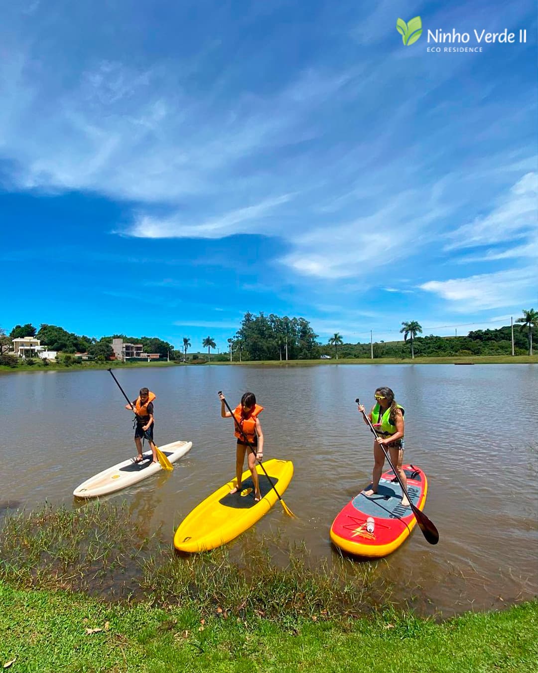 Crianças praticando stand up paddle no lago do Ninho Verde II